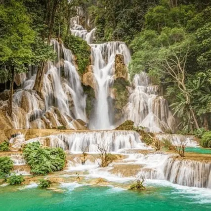 Kuang Si Waterfall in Luang Prabang, with vibrant blue water and sunlight shining on the surface.